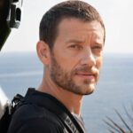 Músico Matthieu Saglio con el violonchelo en la espalda, con el cielo y el mar al fondo. Foto Ana Guimaras