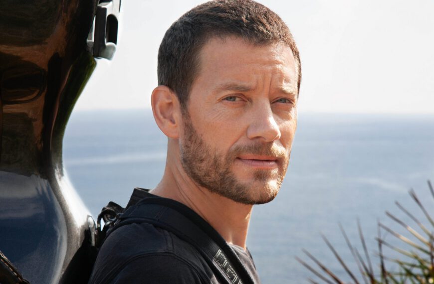 Músico Matthieu Saglio con el violonchelo en la espalda, con el cielo y el mar al fondo. Foto Ana Guimaras