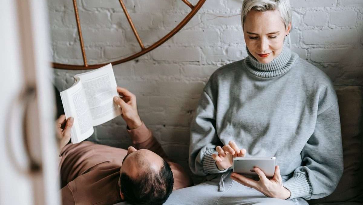 unrecognizable male lying on knees of girlfriend and reading book